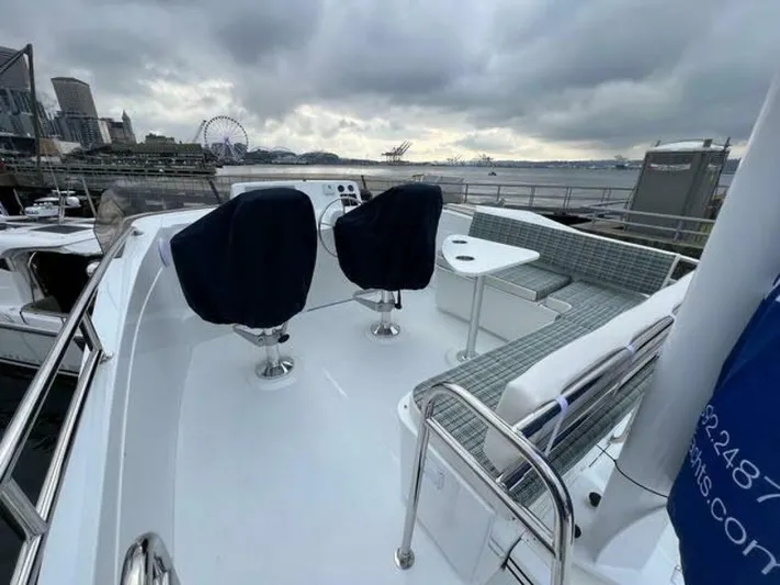 New Boat Hull #12 Yacht Photos Pics 2024 Nordic Tug 40 boat deck with seating, overlooking a waterfront cityscape.