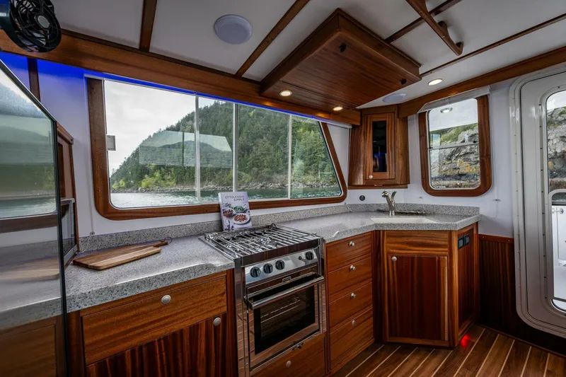 New Boat Hull #12 Yacht Photos Pics 2024 Nordic Tug 40 kitchen with wood cabinetry, modern appliances, and scenic window views.