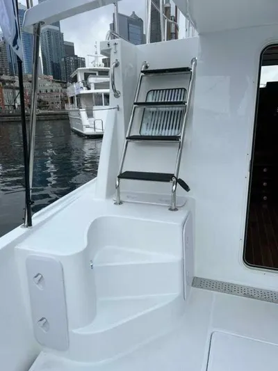 New Boat Hull #12 Yacht Photos Pics 2024 Nordic Tug 40 yacht deck with ladder and cityscape background.