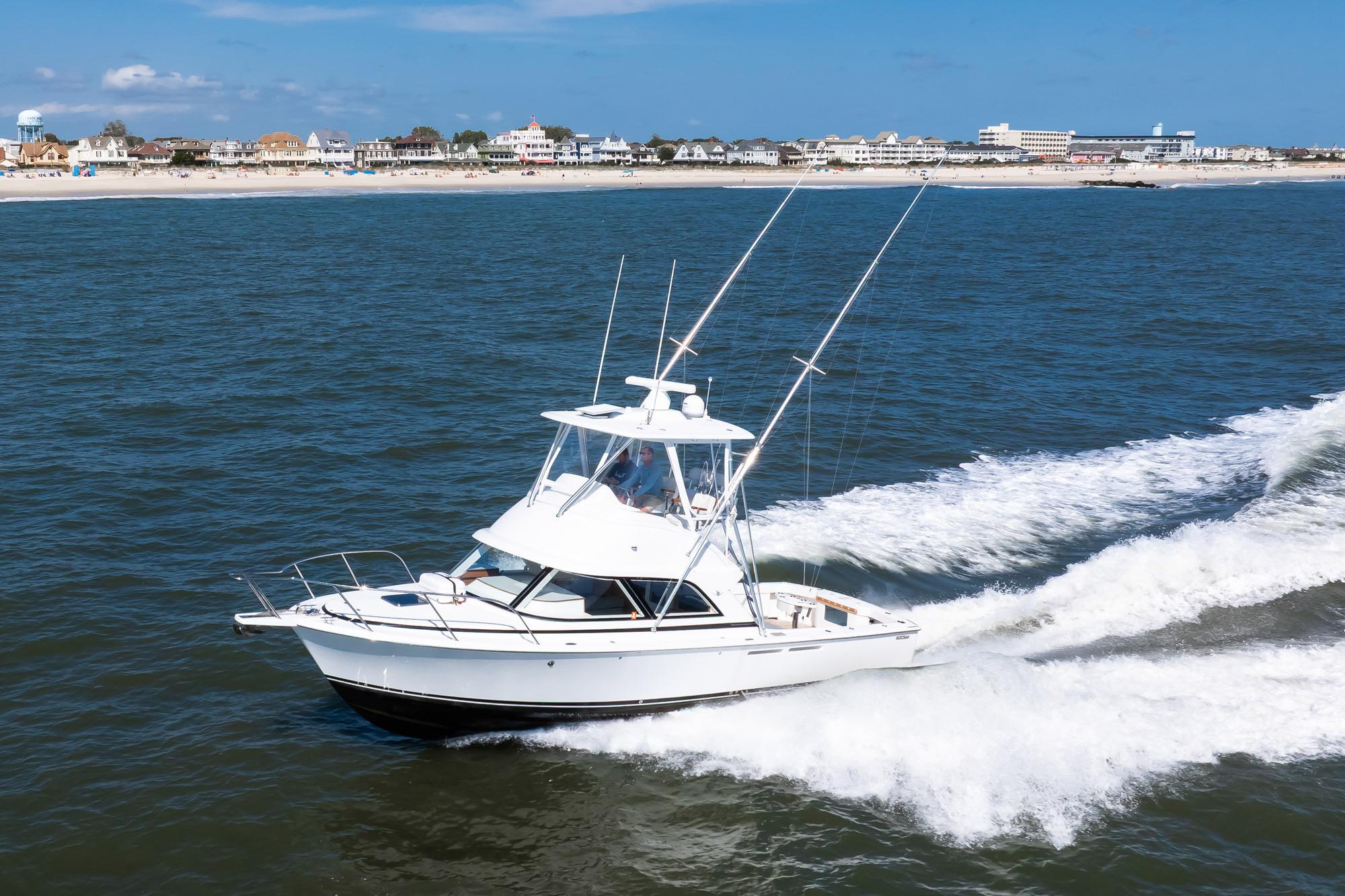 2018 Bertram 35 Flybridge Sportfish cruising near a coastal town.