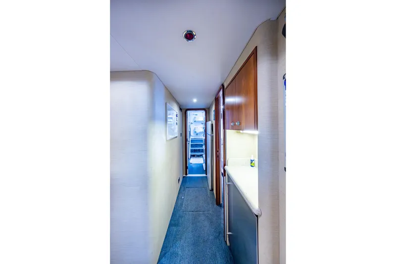 Lila Cuy Yacht Photos Pics Narrow hallway inside 2006 Westport 112 yacht, featuring wood cabinets and carpeted floor.