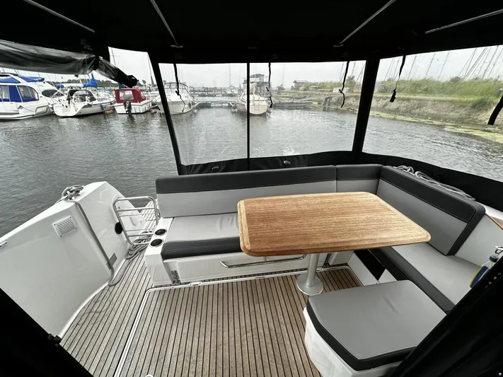  Yacht Photos Pics 2019 Jeanneau Merry Fisher 1095 FLY boat with outdoor seating and wooden table.