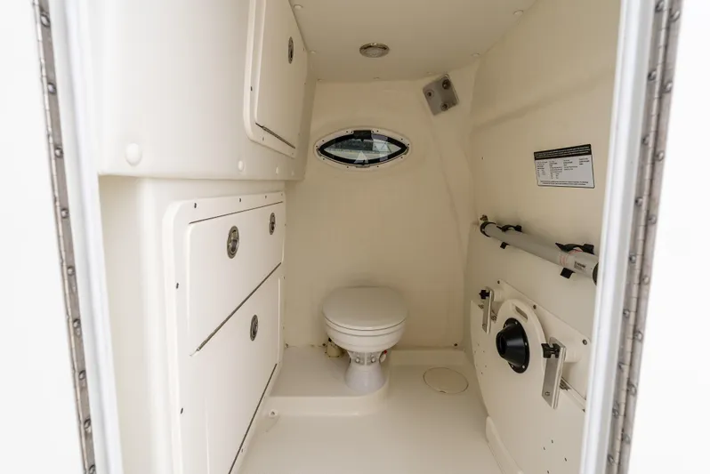  Yacht Photos Pics 2024 World Cat 325 CC boat interior with compact marine toilet and storage cabinets.