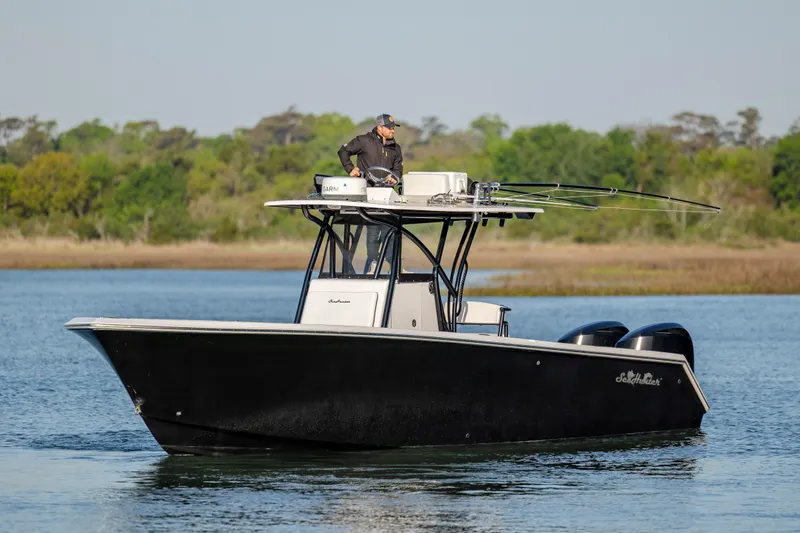  Yacht Photos Pics 2014 SeaHunter 32 Tournament boat on water, with person navigating, surrounded by greenery.