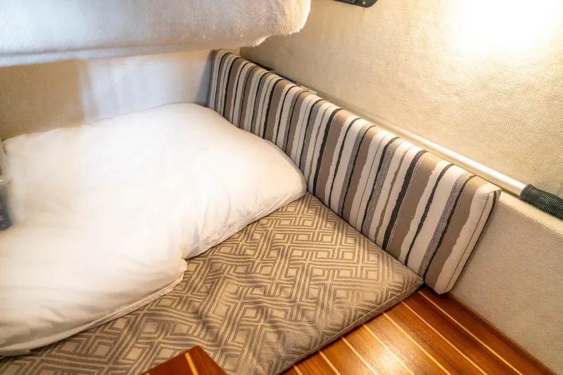  Yacht Photos Pics Cozy cabin interior of 2020 Cutwater C28 boat with striped cushions and wooden flooring.