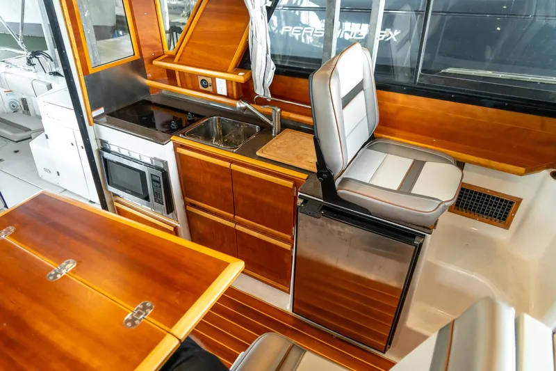  Yacht Photos Pics 2020 Cutwater C28 boat interior with kitchenette, featuring stove, sink, microwave, and seating.