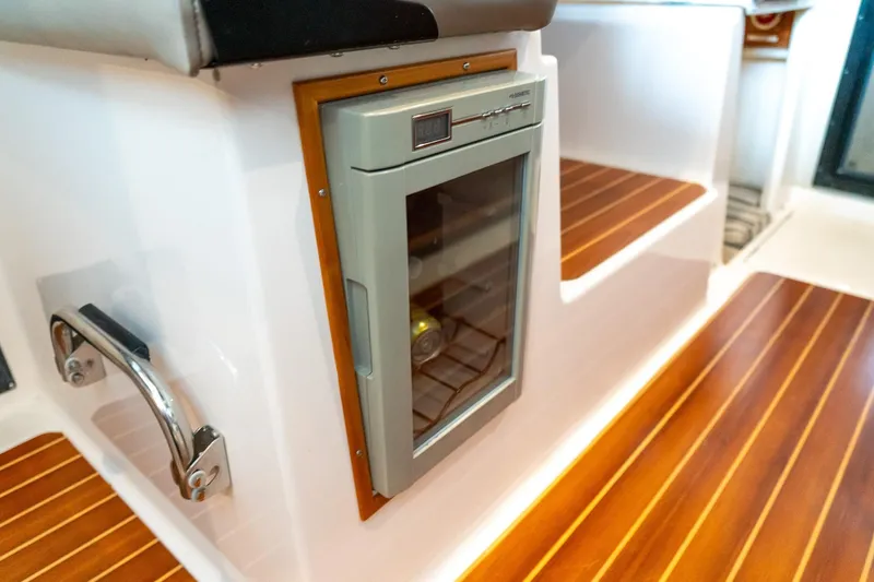  Yacht Photos Pics 2020 Cutwater C28 interior with built-in mini fridge and wooden flooring.