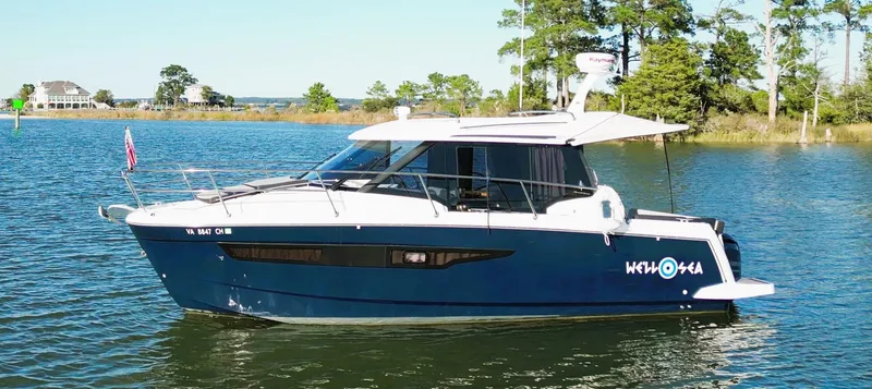  Yacht Photos Pics 2021 Jeanneau NC 895 boat on a serene lake with trees in the background.