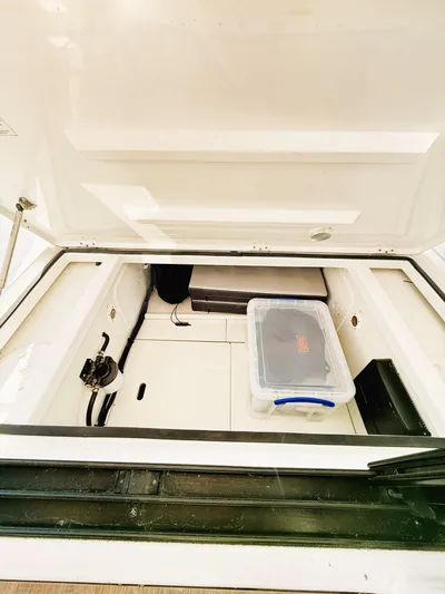  Yacht Photos Pics 2021 Jeanneau NC 895 storage compartment with plastic container inside.