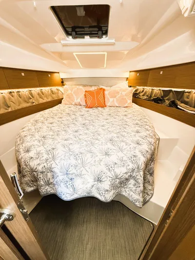  Yacht Photos Pics 2021 Jeanneau NC 895 cabin interior with cozy bed and decorative pillows.