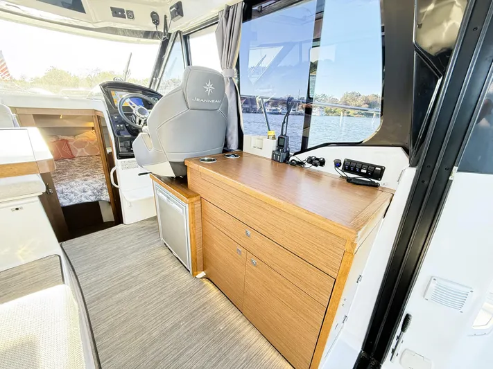  Yacht Photos Pics Interior of 2021 Jeanneau NC 895 boat, featuring helm, wooden cabinetry, and window view.