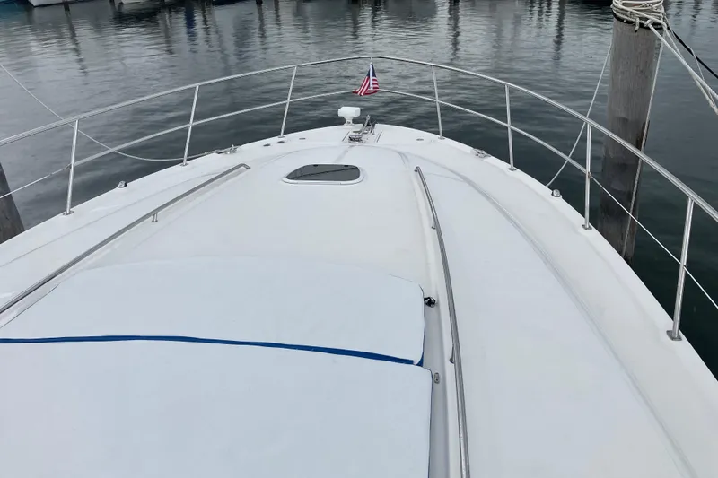 Mafe Yacht Photos Pics 2004 Sea Ray 500 Sundancer yacht bow with American flag, docked in calm waters.