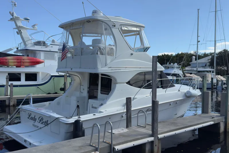  Yacht Photos Pics 2004 Silverton 38 Convertible yacht docked at marina, featuring sleek design and American flag.