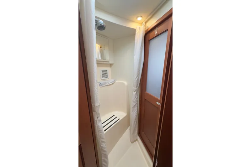  Yacht Photos Pics Shower area in 2004 Silverton 38 Convertible yacht, featuring wooden door and curtain.
