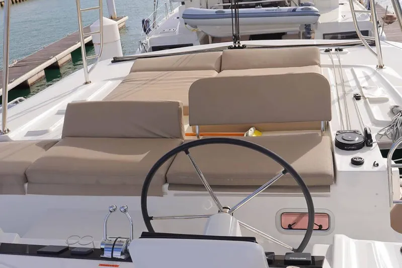  Yacht Photos Pics 2023 Lagoon 46 yacht deck with steering wheel and cushioned seating.