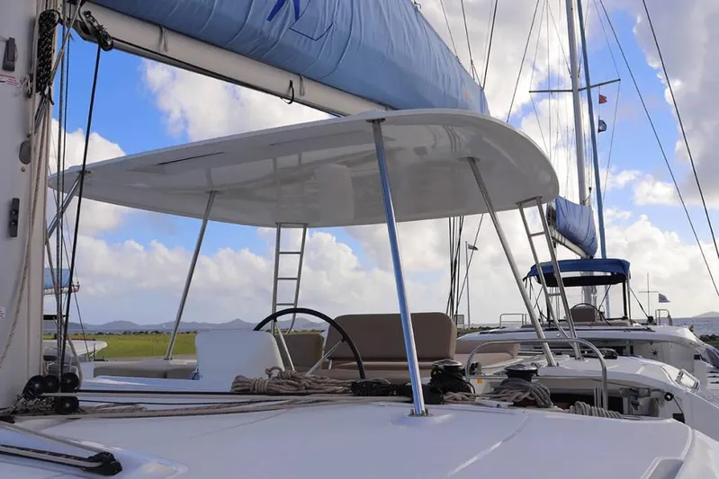  Yacht Photos Pics 2023 Lagoon 46 catamaran with sails, helm, and clear blue sky background.