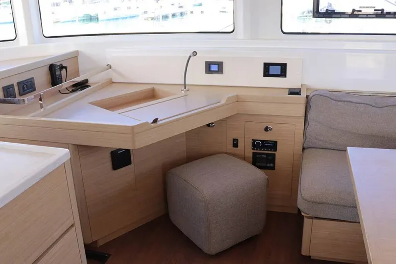  Yacht Photos Pics Modern interior of 2023 Lagoon 46 catamaran with navigation station and seating area.