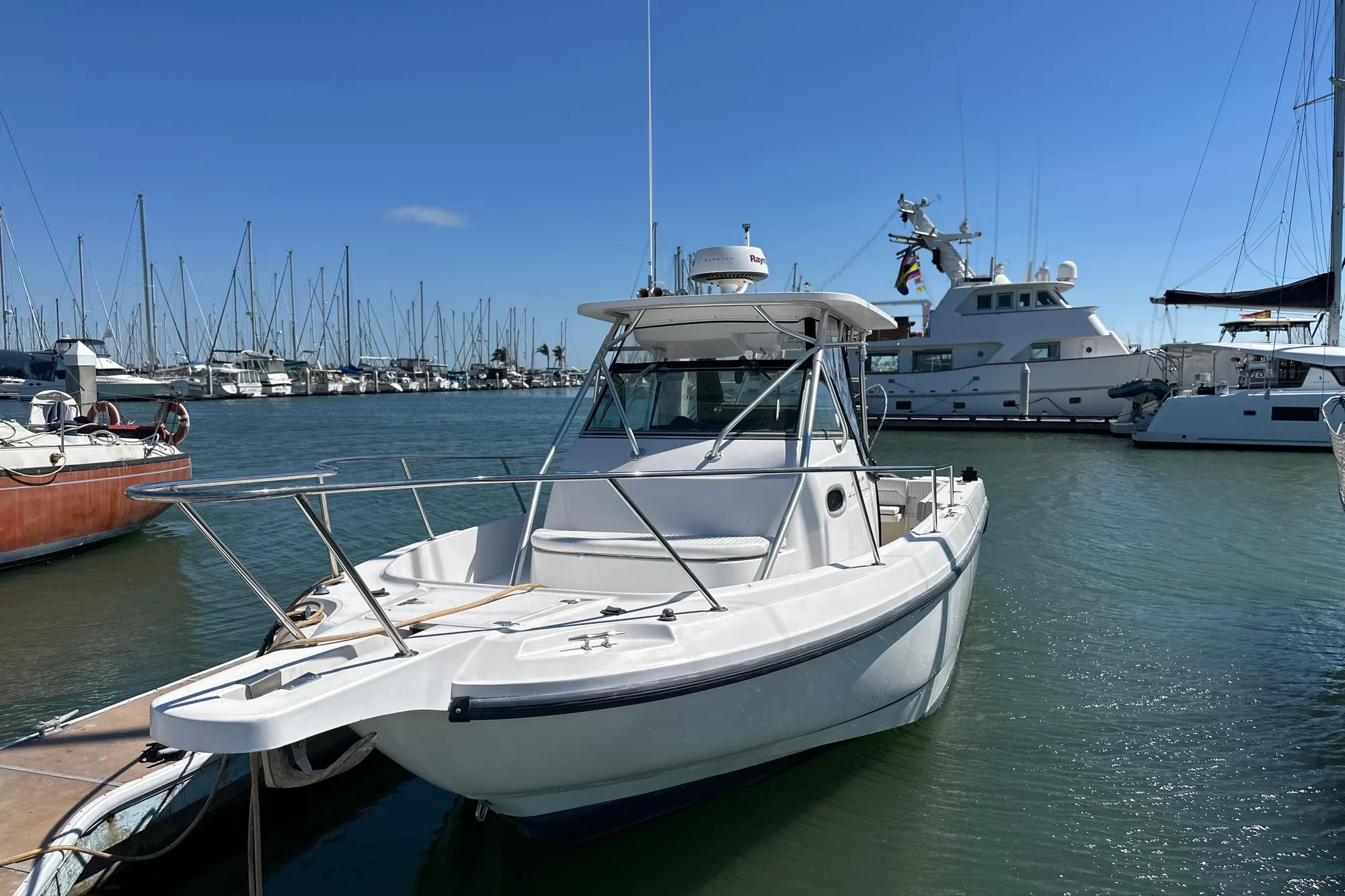 2001 Boston Whaler 28 Outrage boat docked in a marina under clear blue skies.