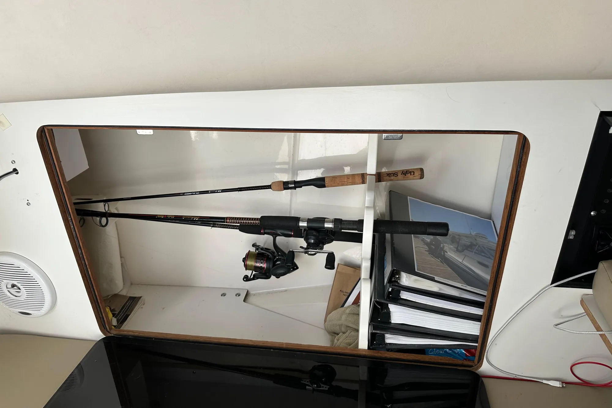 Storage compartment on a 2001 Boston Whaler 28 Outrage with fishing rods and binders.