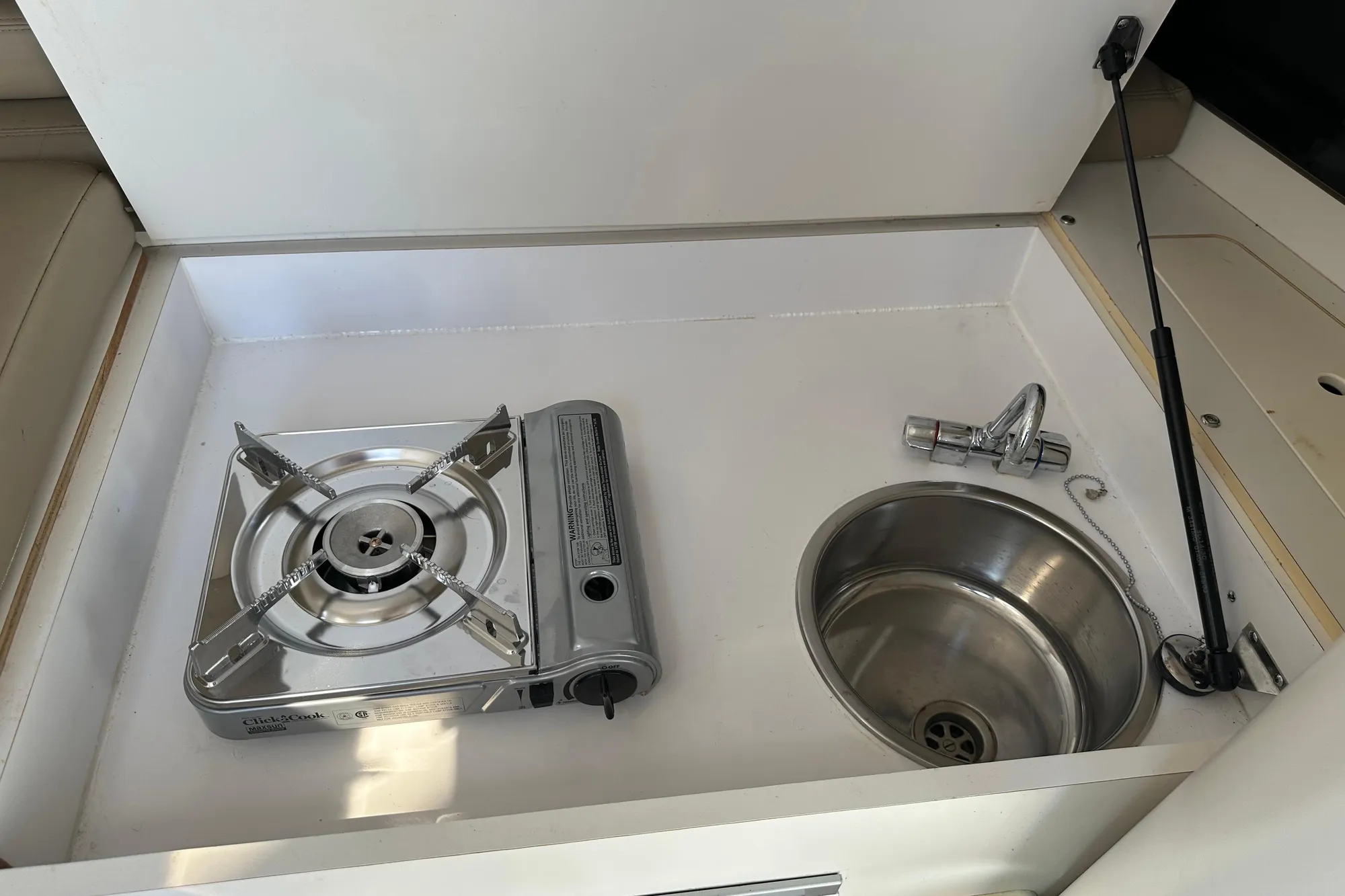 Compact kitchen area on 2001 Boston Whaler 28 Outrage with stove and sink.