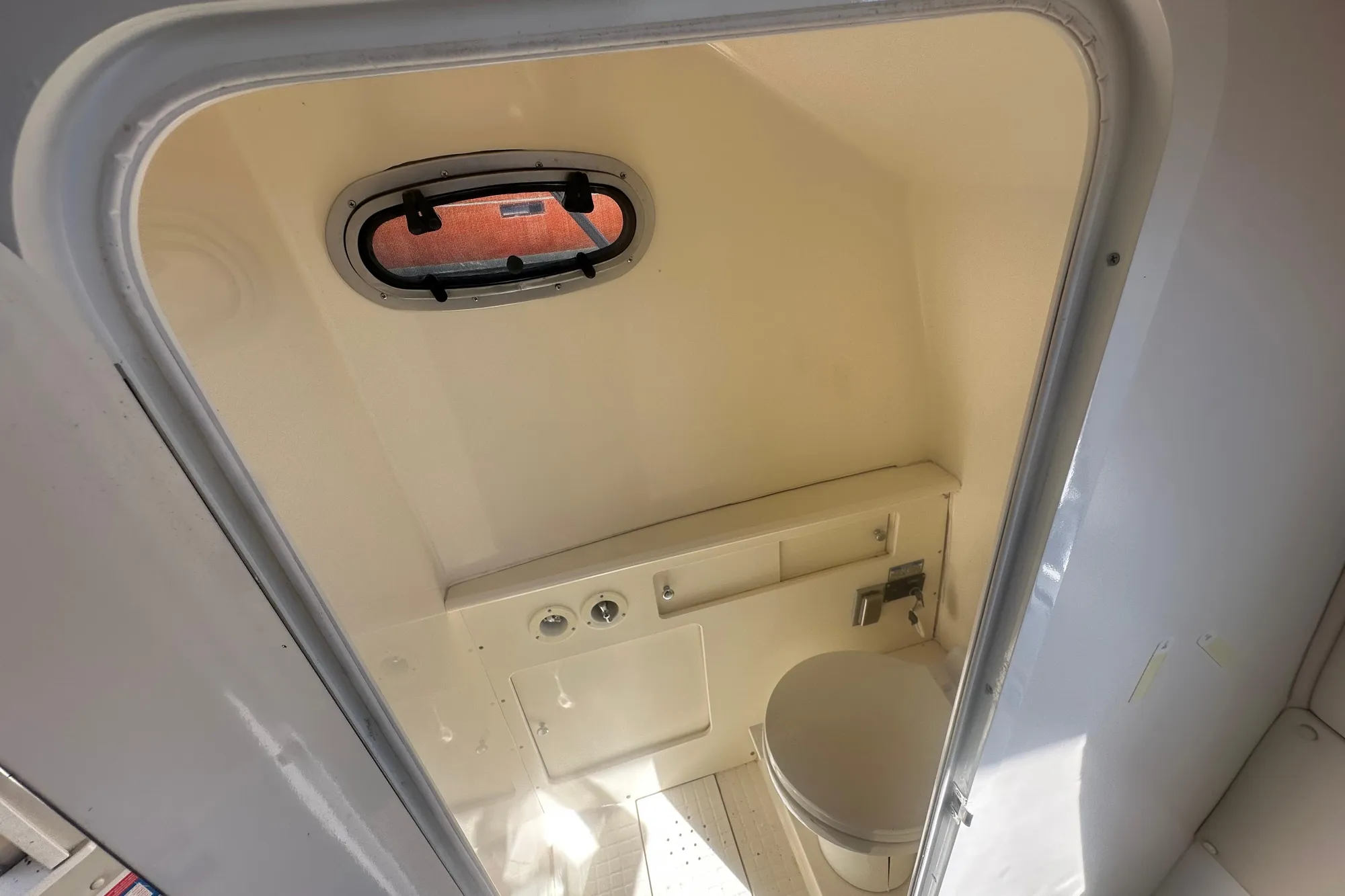 Interior of 2001 Boston Whaler 28 Outrage boat bathroom with porthole window.