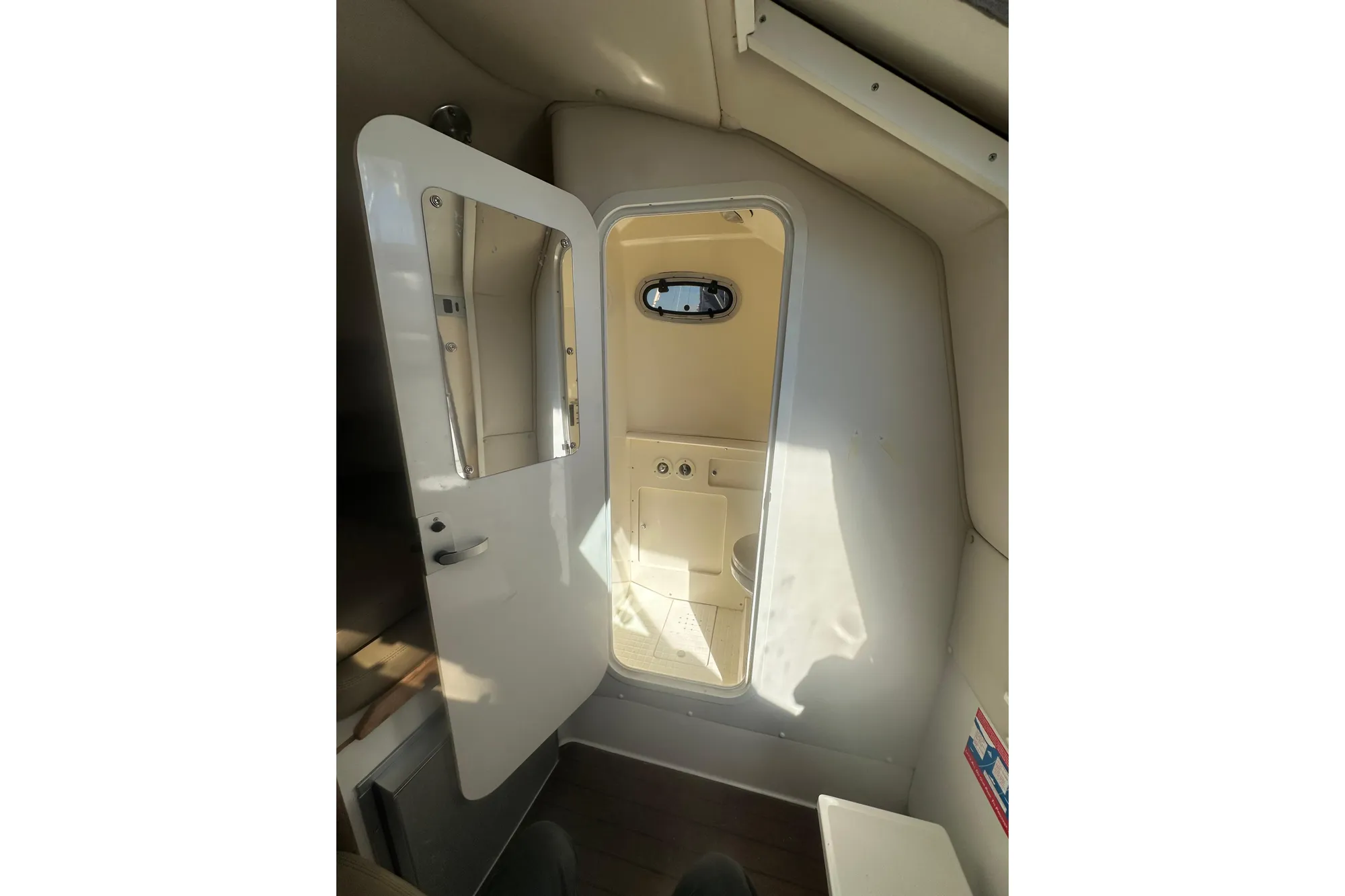 Interior cabin of a 2001 Boston Whaler 28 Outrage boat, featuring a compact restroom.