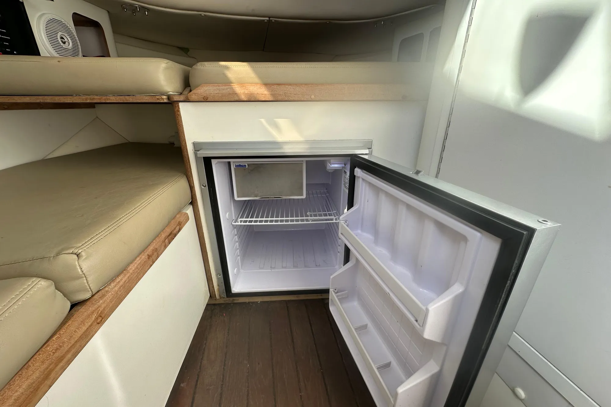 Interior of 2001 Boston Whaler 28 Outrage with open mini fridge and cushioned seating.