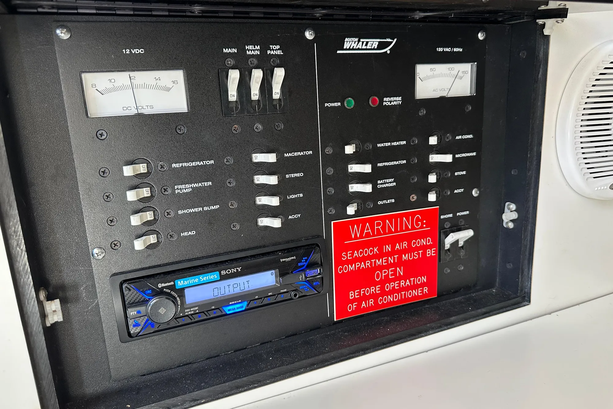 Control panel of a 2001 Boston Whaler 28 Outrage boat with warning sign.