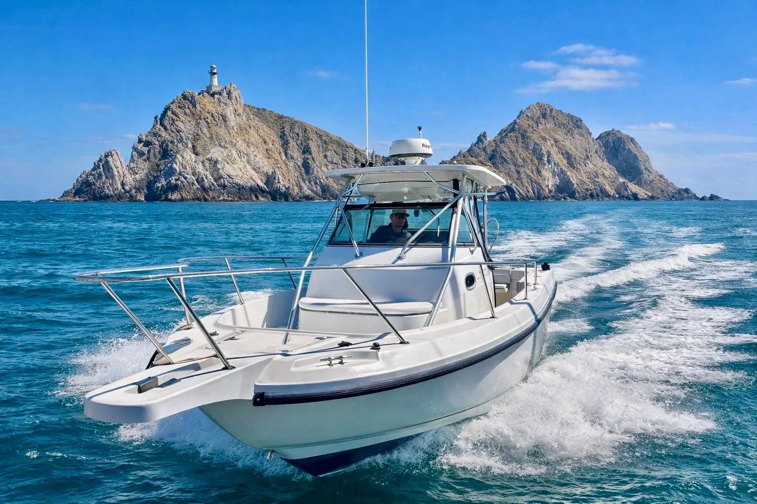 2001 Boston Whaler 28 Outrage cruising near rocky island with lighthouse.
