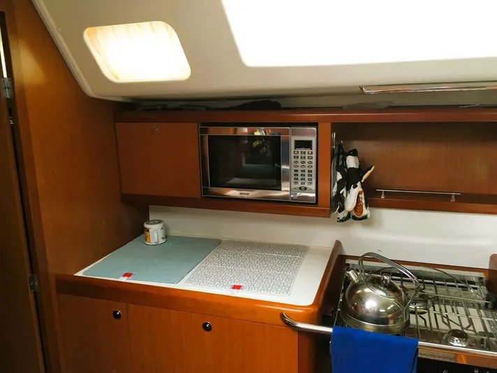  Yacht Photos Pics 2008 Beneteau 49 Oceanis Tall Rig kitchen with microwave, stove, and wooden cabinetry.