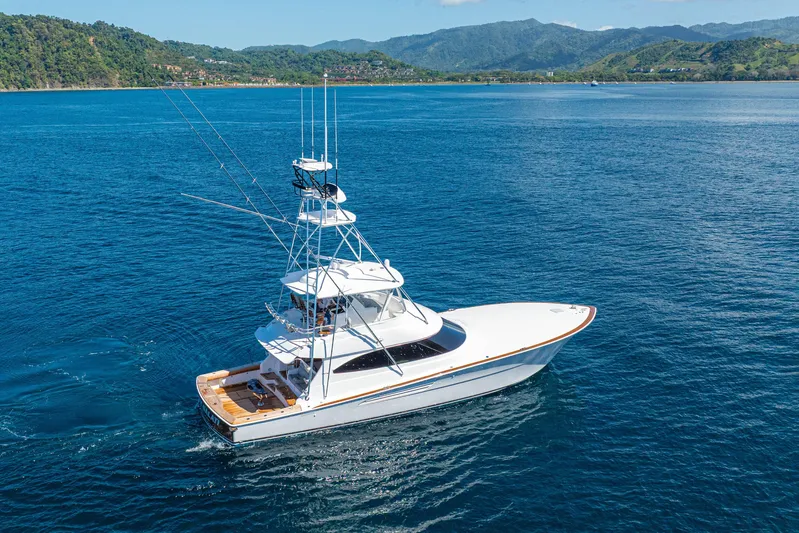 New Viking 64 Convertible Yacht Photos Pics 2026 Viking 64 Convertible yacht cruising on blue ocean near lush green coastline.