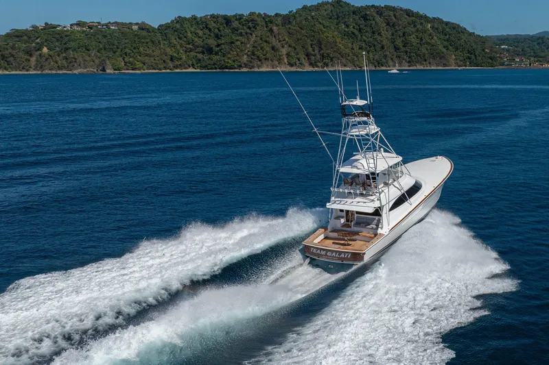 New Viking 64 Convertible Yacht Photos Pics 2026 Viking 64 Convertible yacht cruising on blue ocean near lush green island.