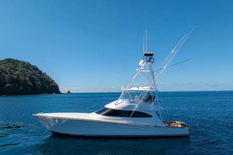 New Viking 64 Convertible Yacht Photos Pics 2026 Viking 64 Convertible yacht cruising on blue ocean near lush island.