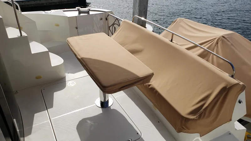 Happy Ours Yacht Photos Pics 2007 Marquis 55 LS yacht deck with beige seating and table, overlooking water.