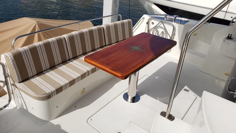 Happy Ours Yacht Photos Pics 2007 Marquis 55 LS yacht deck with striped seating and wooden table.