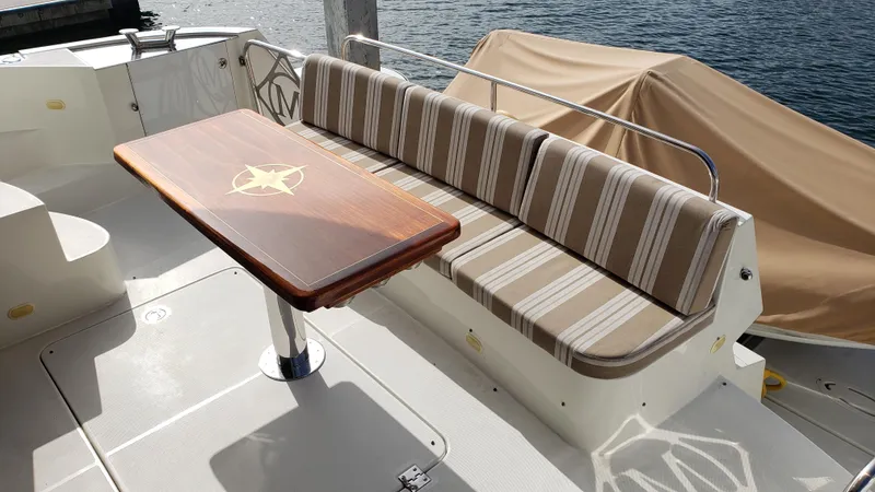 Happy Ours Yacht Photos Pics Luxury seating area on 2007 Marquis 55 LS yacht with striped cushions and wooden table.