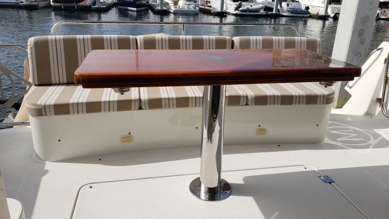 Happy Ours Yacht Photos Pics Luxury seating area on a 2007 Marquis 55 LS yacht with striped cushions and wooden table.