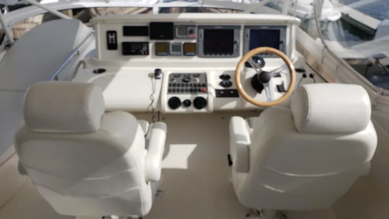 Happy Ours Yacht Photos Pics Cockpit of 2007 Marquis 55 LS yacht with dual white captain chairs and control panel.