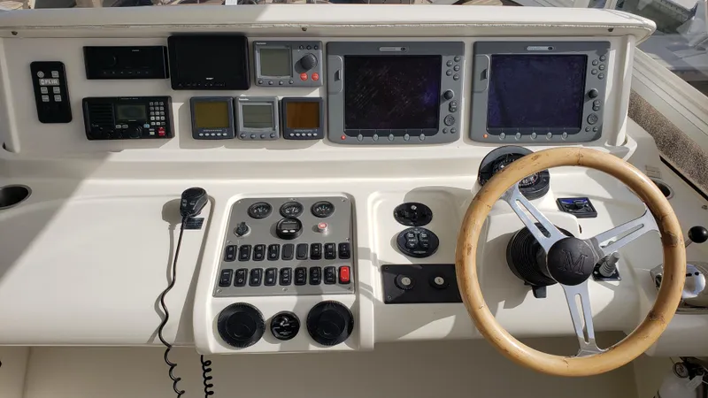 Happy Ours Yacht Photos Pics Control panel of a 2007 Marquis 55 LS yacht with steering wheel and navigation instruments.