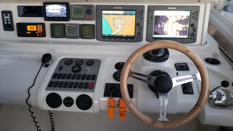 Happy Ours Yacht Photos Pics 2007 Marquis 55 LS yacht helm with navigation screens, controls, and wooden steering wheel.