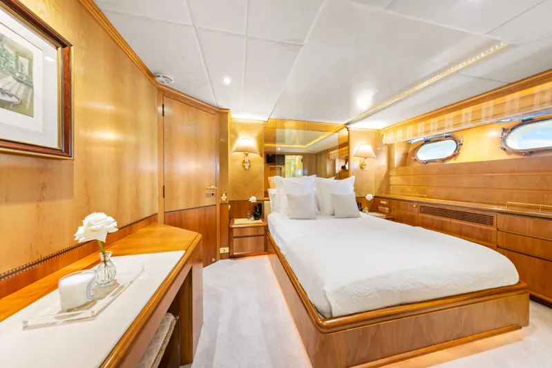 Mistress Yacht Photos Pics Luxurious bedroom interior on a 1991 Benetti 46m yacht, featuring elegant wood paneling and plush bedding.
