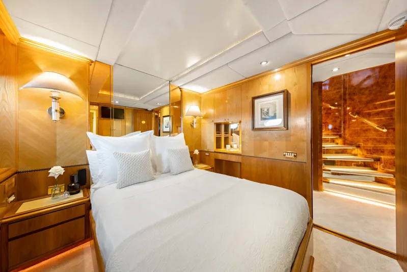 Mistress Yacht Photos Pics Luxurious bedroom on a 1991 Benetti 46m yacht with elegant wood paneling and plush bedding.