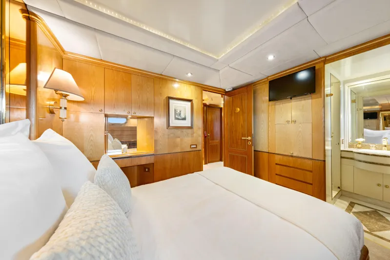 Mistress Yacht Photos Pics Luxurious bedroom interior on a 1991 Benetti 46m yacht, featuring elegant wood paneling.