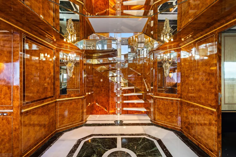 Mistress Yacht Photos Pics Luxurious interior of 1991 Benetti 46m yacht with elegant wood paneling and spiral staircase.