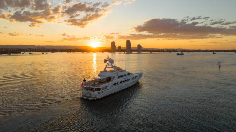 Mistress Yacht Photos Pics Luxurious 1991 Benetti 46m yacht cruising at sunset with city skyline backdrop.