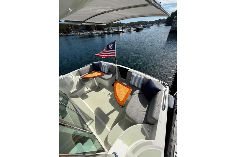 Luna Yacht Photos Pics 2020 Back Cove 37 boat with cushioned seating, wooden tables, and American flag on calm water.