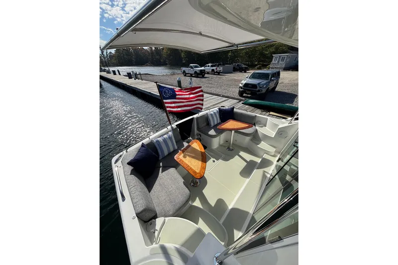 Luna Yacht Photos Pics 2020 Back Cove 37 boat with American flag, docked by a scenic waterfront.