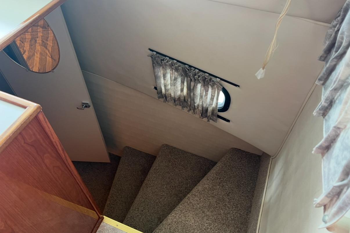 Staircase inside 2002 Harbor Master 440 Widebody yacht with carpet and small window.