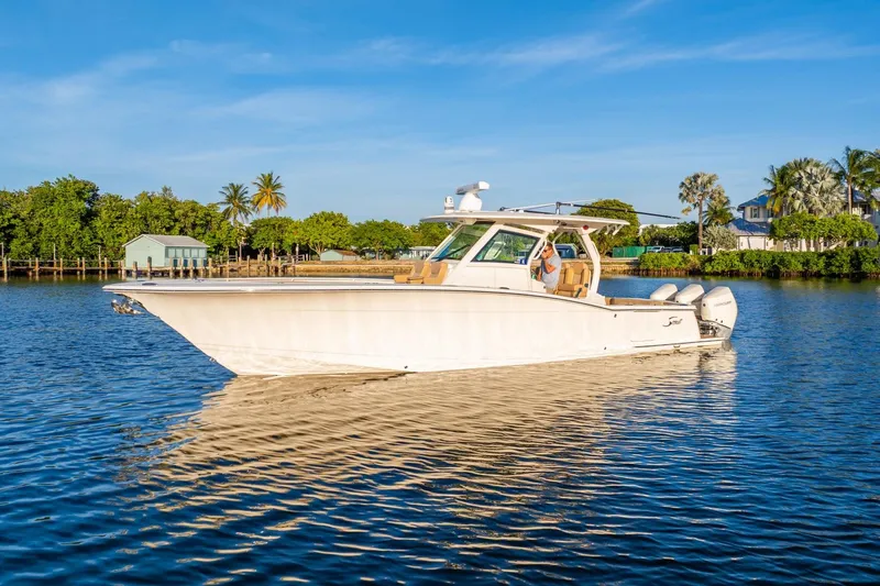  Yacht Photos Pics 2020 Scout 355 LXF boat cruising on a sunny day, surrounded by lush greenery.