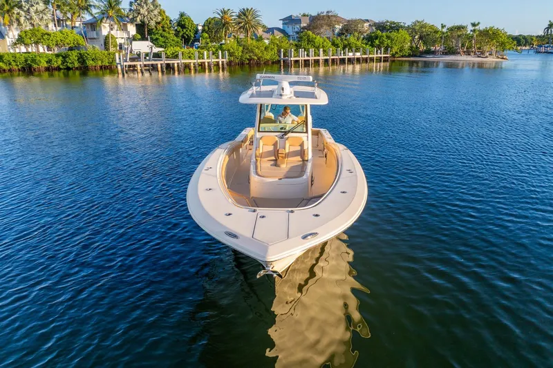  Yacht Photos Pics 2020 Scout 355 LXF boat cruising on a serene waterway with lush greenery.